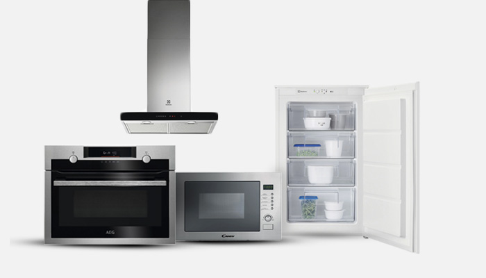 Elettrodomestici su sfondo bianco: forno, microonde, cappa aspirante in metallo e frigorifero bianco aperto.