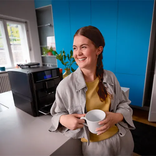 un addetto in maglia rossa presenta delle macchine del caffe' ad un cliente in camicia blu. Sono all'interno di un negozio