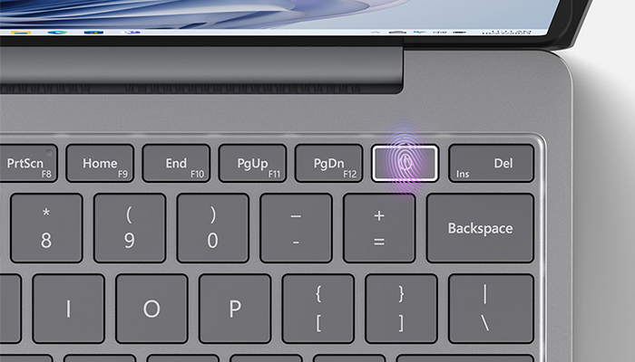 Tastiera grigia di un laptop con tasto di impronta digitale evidenziato e altri tasti funzione visibili.
