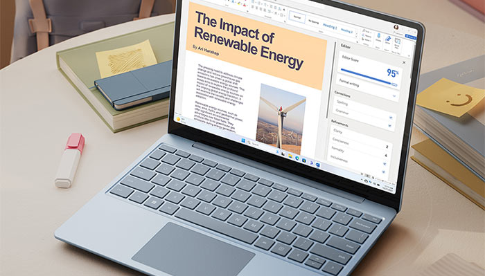 Laptop aperto su tavolo con documenti. Lo schermo mostra un testo su energia rinnovabile. Blocco note e evidenziatore accanto.