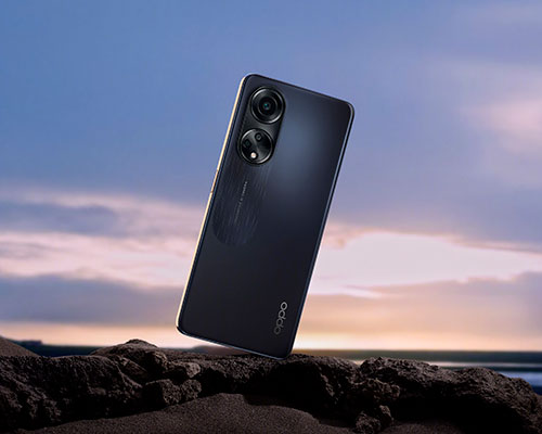 Telefono nero su roccia, con due fotocamere posteriori visibili. Sullo sfondo, cielo al tramonto e mare.