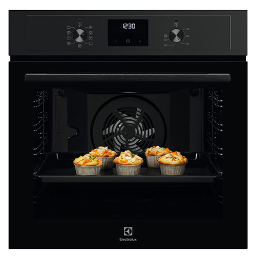 Forno nero con display digitale che mostra l'ora, teglia con cinque muffin. Ventola visibile.