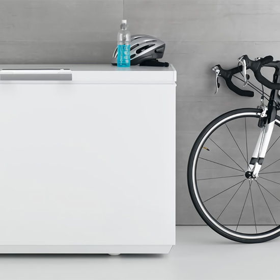 Frigorifero bianco con casco, spray e bicicletta da corsa. Lo sfondo � grigio chiaro.