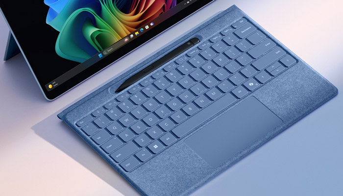 Tablet con schermo acceso e tastiera blu. Una penna nera è appoggiata sopra la tastiera. Lo sfondo è chiaro.