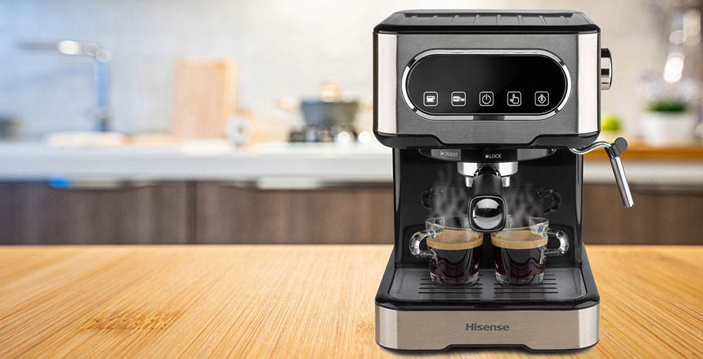 Macchina da caff� Hisense su tavolo di legno con due tazzine riempite di caff�. Sullo sfondo, una cucina.