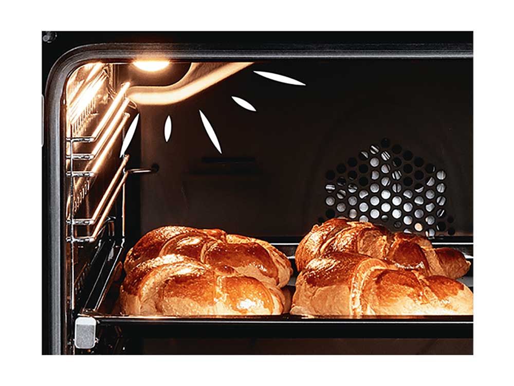 Due pani dorati su una teglia in forno illuminato. Griglia di ventilazione visibile sullo sfondo nero.