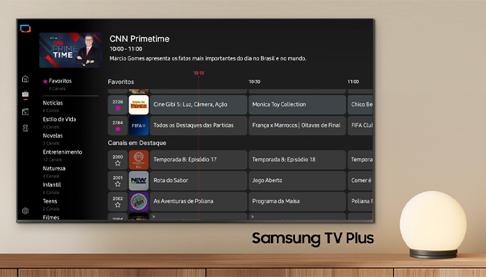 Schermo TV con menu Samsung TV Plus, lampada sferica su mobile in legno.