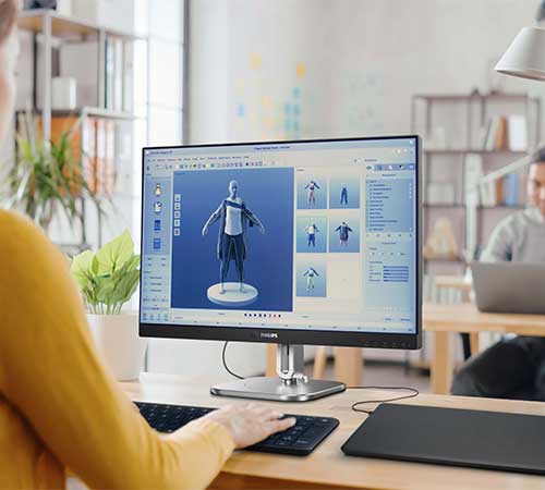 Donna che usa un computer con un modello 3D. Tastiera e tavoletta grafica sul tavolo. Libreria sullo sfondo.