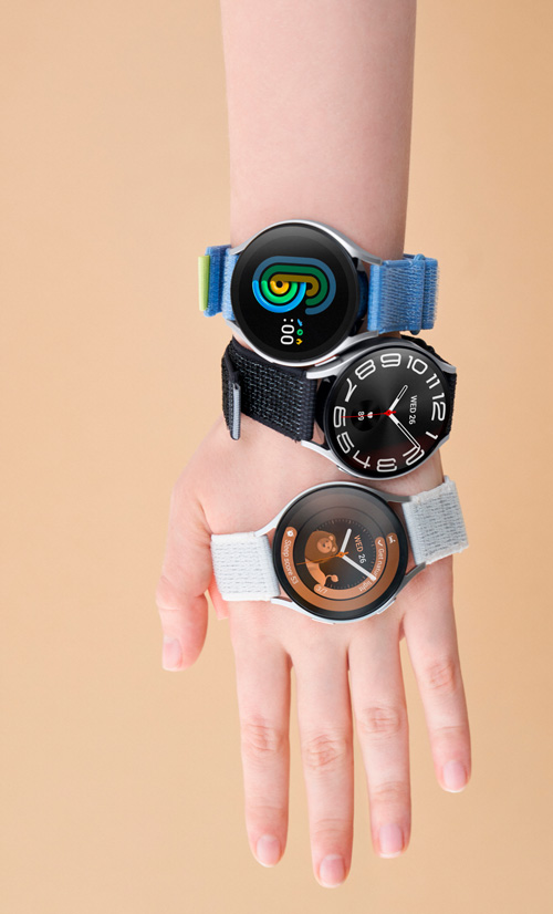 Una mano con tre orologi da polso impilati. I cinturini sono blu, nero e bianco. Gli schermi degli orologi mostrano diversi display.