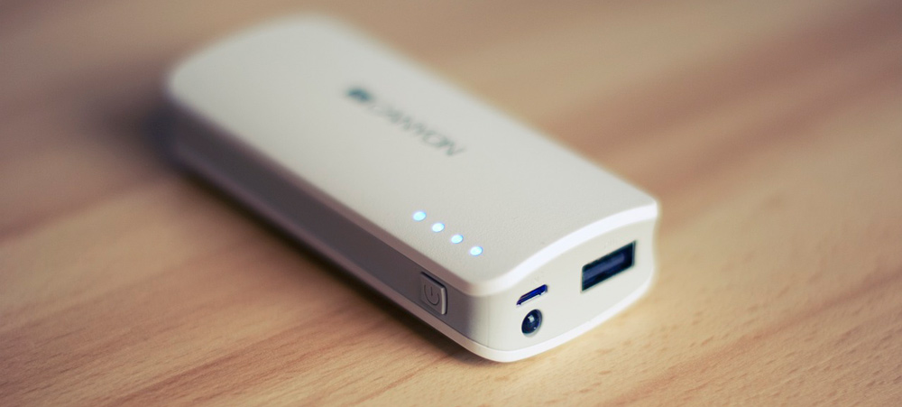 Batteria portatile bianca su superficie di legno. Quattro spie luminose e porte USB visibili.