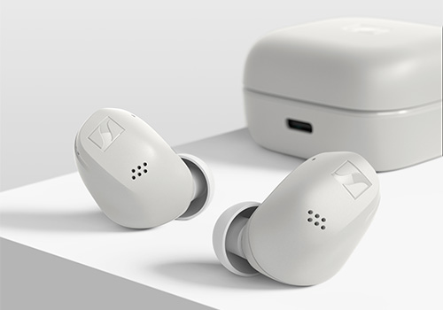 Due auricolari bianchi e custodia di ricarica su superficie bianca. Gli auricolari hanno fori per audio e sensori.