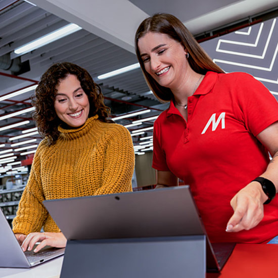 Una commessa MediaWorld che mostra ad una cliente un notebook