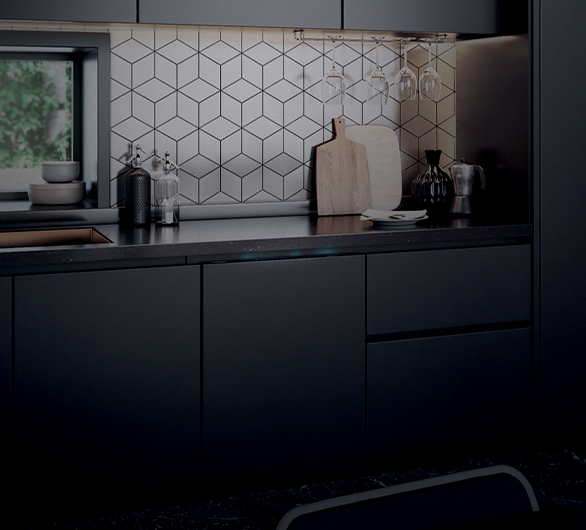 Cucina scura con alzatina a motivi geometrici, taglieri in legno, bicchieri appesi e accessori da cucina sul piano di lavoro.