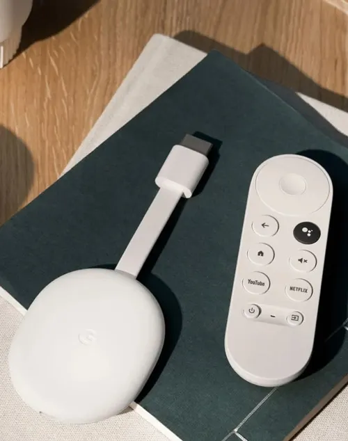 Dispositivo bianco con cavo, telecomando su libro blu, su tavolo di legno.