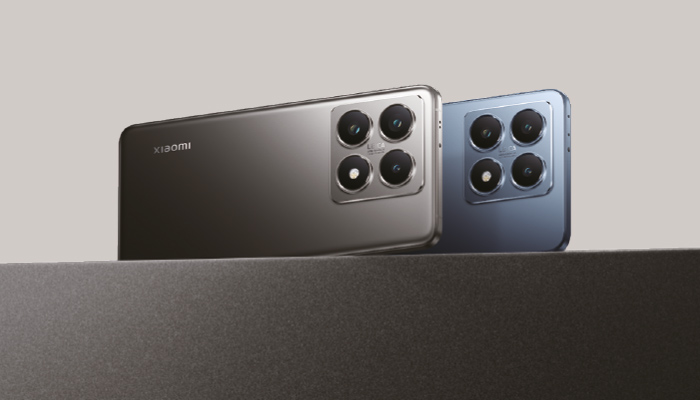 Due telefoni Xiaomi grigi e blu con quattro fotocamere ciascuno su una superficie scura.