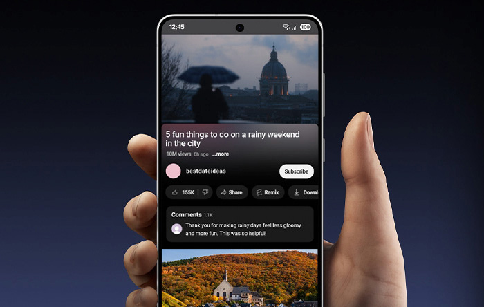 Mano che tiene un telefono che mostra un video di YouTube con suggerimenti per un weekend piovoso in città.