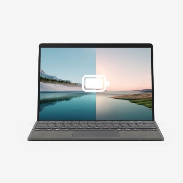 Un laptop grigio mostra un'immagine divisa di un paesaggio con un'icona di batteria scarica sovrapposta allo schermo.