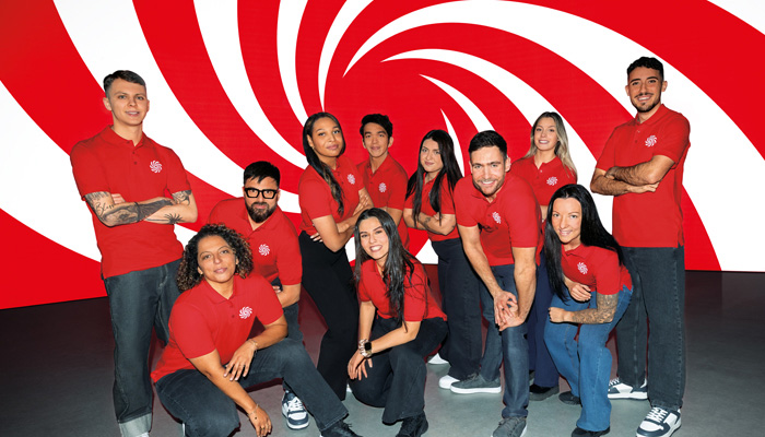 Cinque persone in maglietta rossa e jeans posano sorridendo.