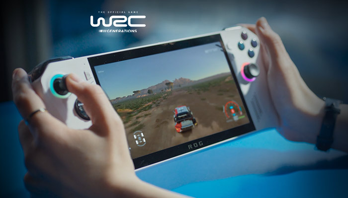 Due mani tengono una console portatile bianca. Lo schermo mostra un gioco di corse automobilistiche su un terreno collinare.