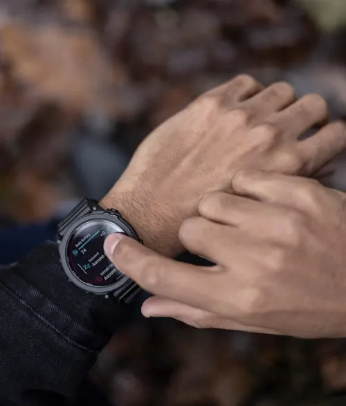 Primo piano di un uomo che interagisce con uno smartwatch nero su sfondo sfocato.