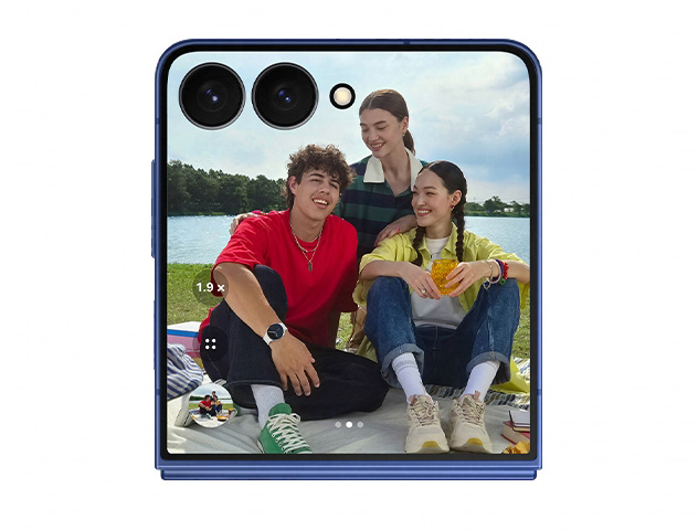 foto di tre ragazzi, che fanno picnic, un ragazzo e due ragazze sedute e sullo sfondo un lago e alberi