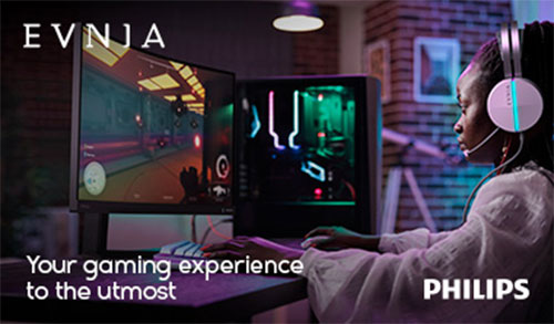 Ragazza con cuffie gioca su PC con monitor e luci LED. Tavolo viola, sfondo con mattoni e poster. Marchi EVNJA e PHILIPS.