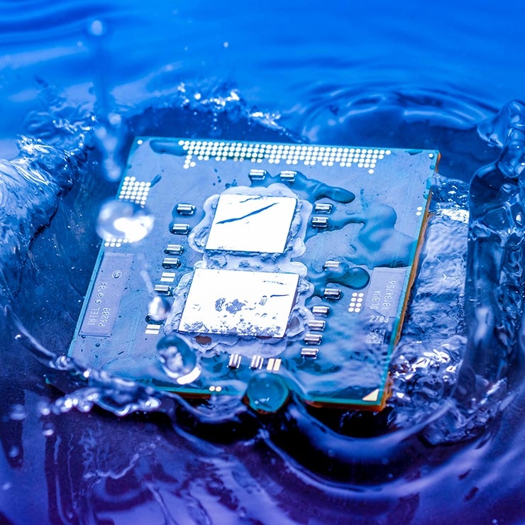 Un chip di computer blu con due processori � immerso nell'acqua, creando schizzi e gocce visibili.