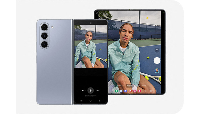 Un telefono pieghevole grigio accanto a un tablet nero che mostra una persona su un campo da tennis.