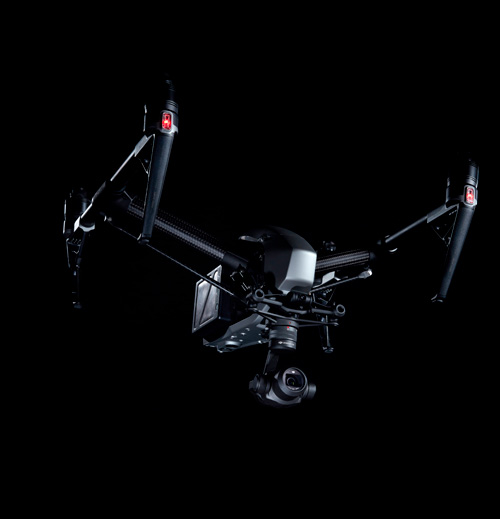 Drone nero con bracci estesi e camera stabilizzata, su sfondo nero. Luci rosse visibili sui bracci.