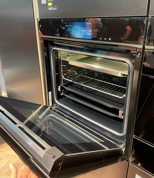 Forno nero con porta aperta, ripiani interni e schermo digitale visibile.