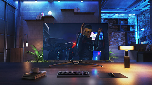 Scrivania con monitor che mostra una persona in azione, tastiera, mousepad, lampada e tazza su libri. Illuminazione blu ambientale.