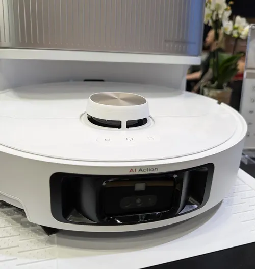 Primo piano di un robot aspirapolvere bianco con dettagli neri e grigi, e una base di ricarica grigia.