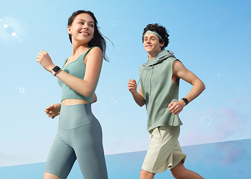 Una donna e un uomo corrono indossando abbigliamento sportivo e smartwatch su uno sfondo azzurro.