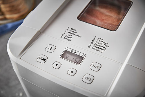 Macchina del pane bianca con display digitale che mostra "4:50". I pulsanti includono impostazioni per vari tipi di pane.