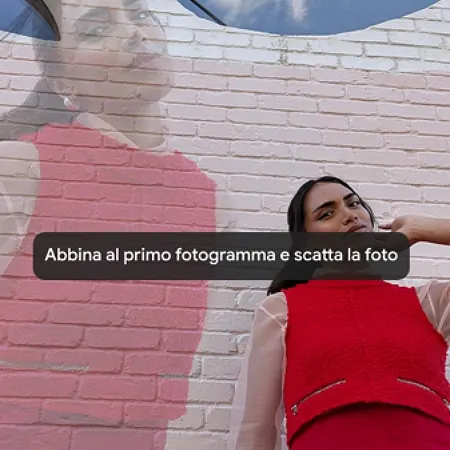 una donna vestita di rosso sorride all'obbiettivo e dietro di lei un muro