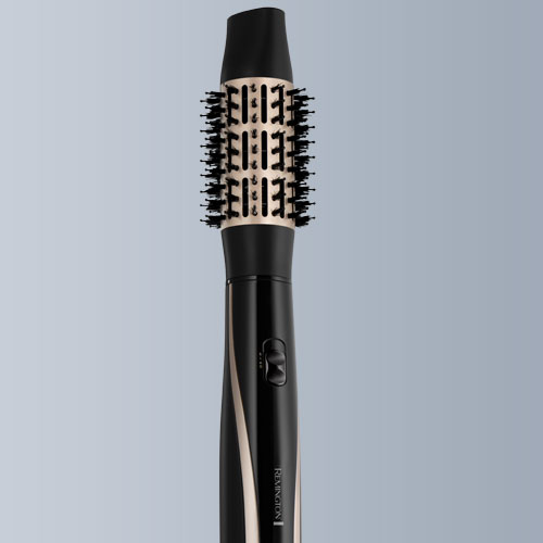 Spazzola ad aria calda nera e oro con setole nere su sfondo sfumato grigio.