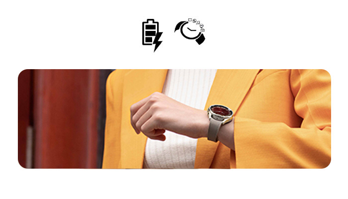 Icone di batteria e orologio sopra un'inquadratura di una persona con giacca gialla e orologio al polso.