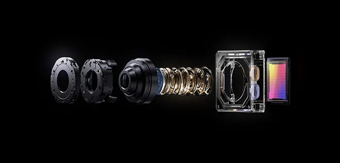 Obiettivi di fotocamera smontati su sfondo nero. Gli elementi includono anelli, lenti, spirali e un prisma colorato.