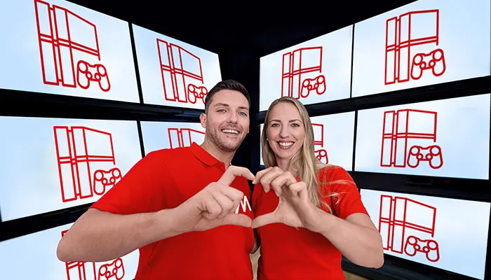 Uomo e donna sorridono in magliette rosse, formando un cuore con le mani. Dietro, schermi con icone rosse di finestre e controller.