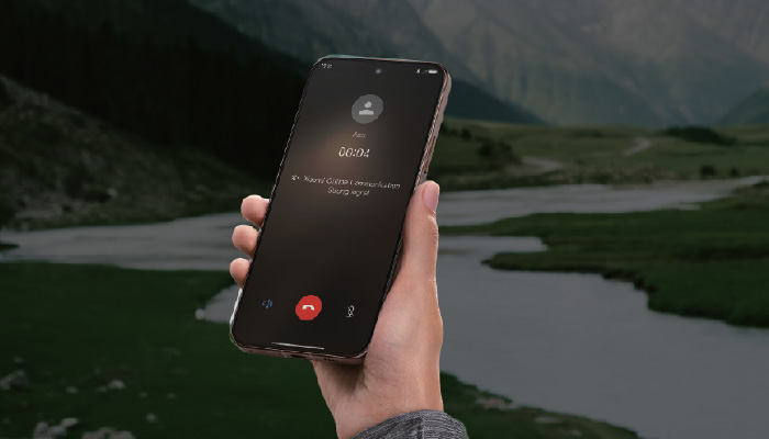 mano che tiene un telefono xiaomi in chiamata e sullo sfondo un paesaggio di natura: montagna e lago
