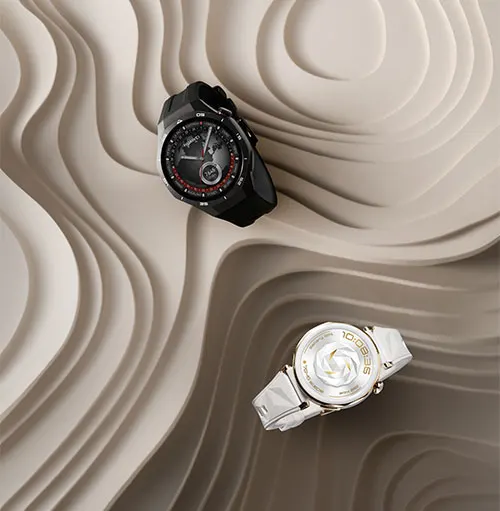 Due orologi su sfondo beige ondulato. Uno nero con dettagli rossi, l'altro argentato con quadrante bianco.