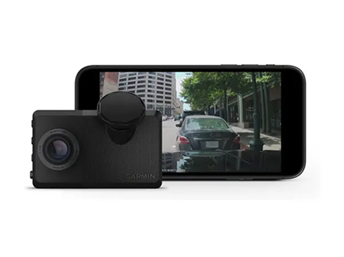 Una telecamera nera compatta � accanto a uno smartphone. Lo schermo dello smartphone mostra una strada cittadina con un'auto.