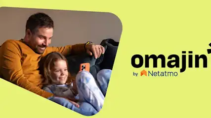 Padre e figlia sorridono su un divano. L'uomo indossa una maglia arancione. Logo "Omajin by Netatmo" su sfondo giallo.