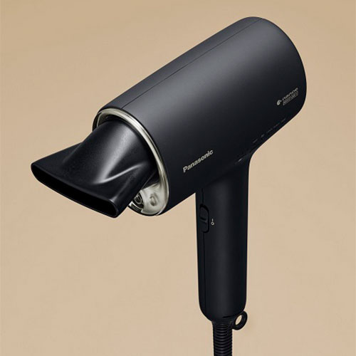 Un asciugacapelli nero su sfondo beige, con beccuccio direzionatore e cavo spiralato.