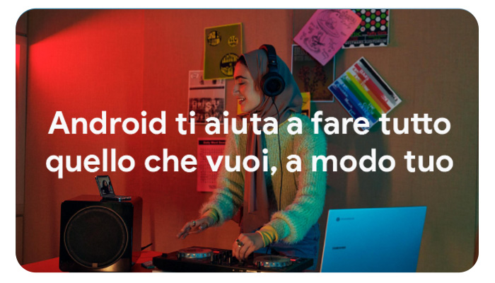 Una persona con cuffie mixa musica su un giradischi, con laptop blu e speaker neri vicini. Muro con poster colorati sullo sfondo.