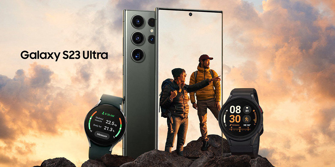 Due smartphone e due orologi smart su rocce. Un telefono mostra persone che fanno escursioni. Nuvole sullo sfondo.