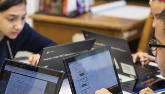 Ragazzi che utilizzano computer portatili neri in un ambiente scolastico. Sullo sfondo, un tavolo di legno.