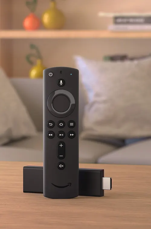 Telecomando nero su tavolo di legno con dispositivo e divano sullo sfondo.