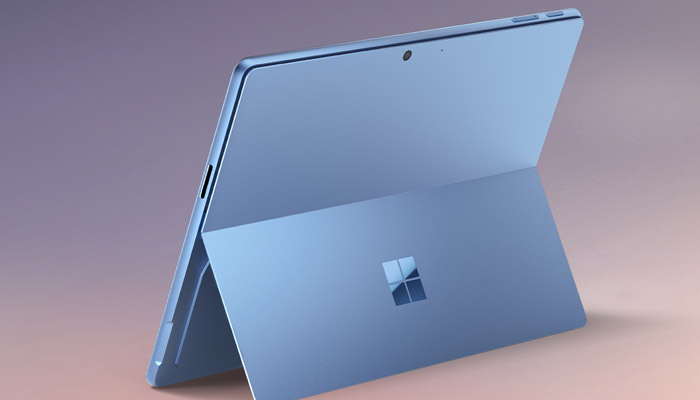 Un tablet blu chiaro è appoggiato su un supporto integrato, con il logo Microsoft visibile sul retro. Sfondo sfumato.