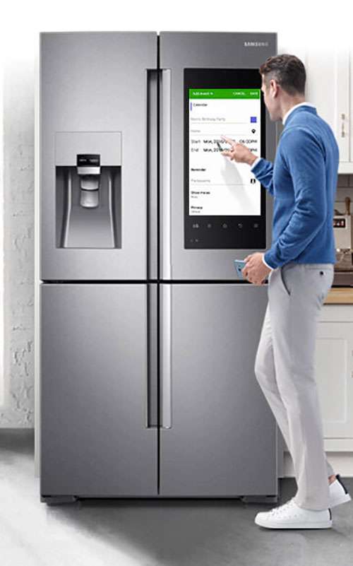 Un frigorifero Samsung in acciaio inossidabile con schermo touch. Un uomo interagisce con lo schermo.